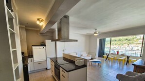 A modern kitchen with a central island, a dining area with yellow stools, and a view of a marina through large windows. - 2-Bedroom Apartment with Sea View – Everything Within Walking Distance (ST MANDRIER SUR MER)
