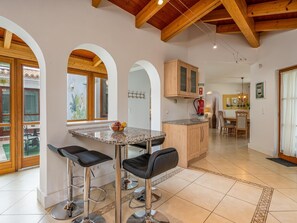 Una cocina moderna con encimera de mármol, dos taburetes de bar y armarios de madera.