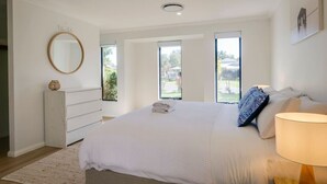 Een slaapkamer met een groot bed, een bedlamp, een dressoir en een raam met uitzicht.