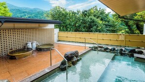 A traditional Japanese onsen with a stone bath, a small hot spring, and a wooden fence. - Jinzukyo Kasuga Onsen Tominowa (Toyama)