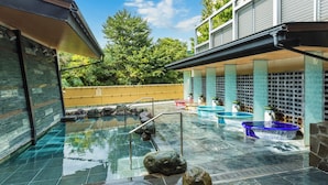 A modern outdoor pool area with clear water, stone features, and a wooden deck. - Jinzukyo Kasuga Onsen Tominowa (Toyama)