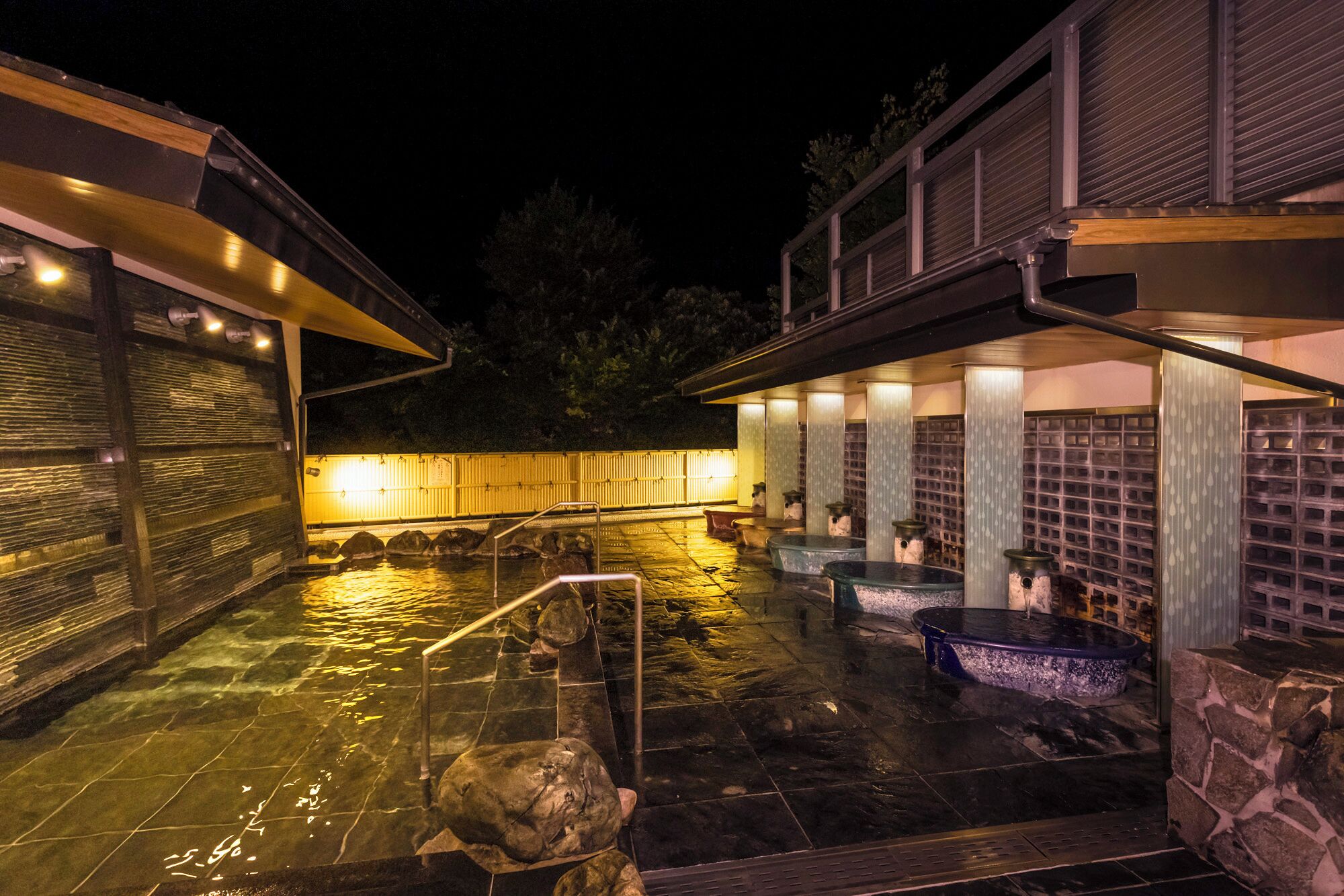 A heated outdoor pool area with stone steps and multiple hot tubs.