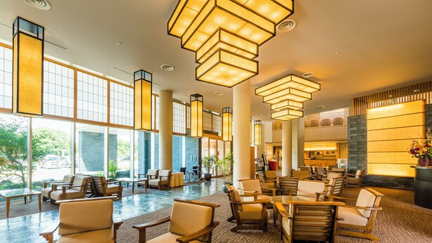 A spacious lobby with high ceilings, large windows, and modern furniture. - Jinzukyo Kasuga Onsen Tominowa (Toyama)