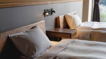 A hotel room with two beds, a nightstand, and a wall-mounted light fixture.