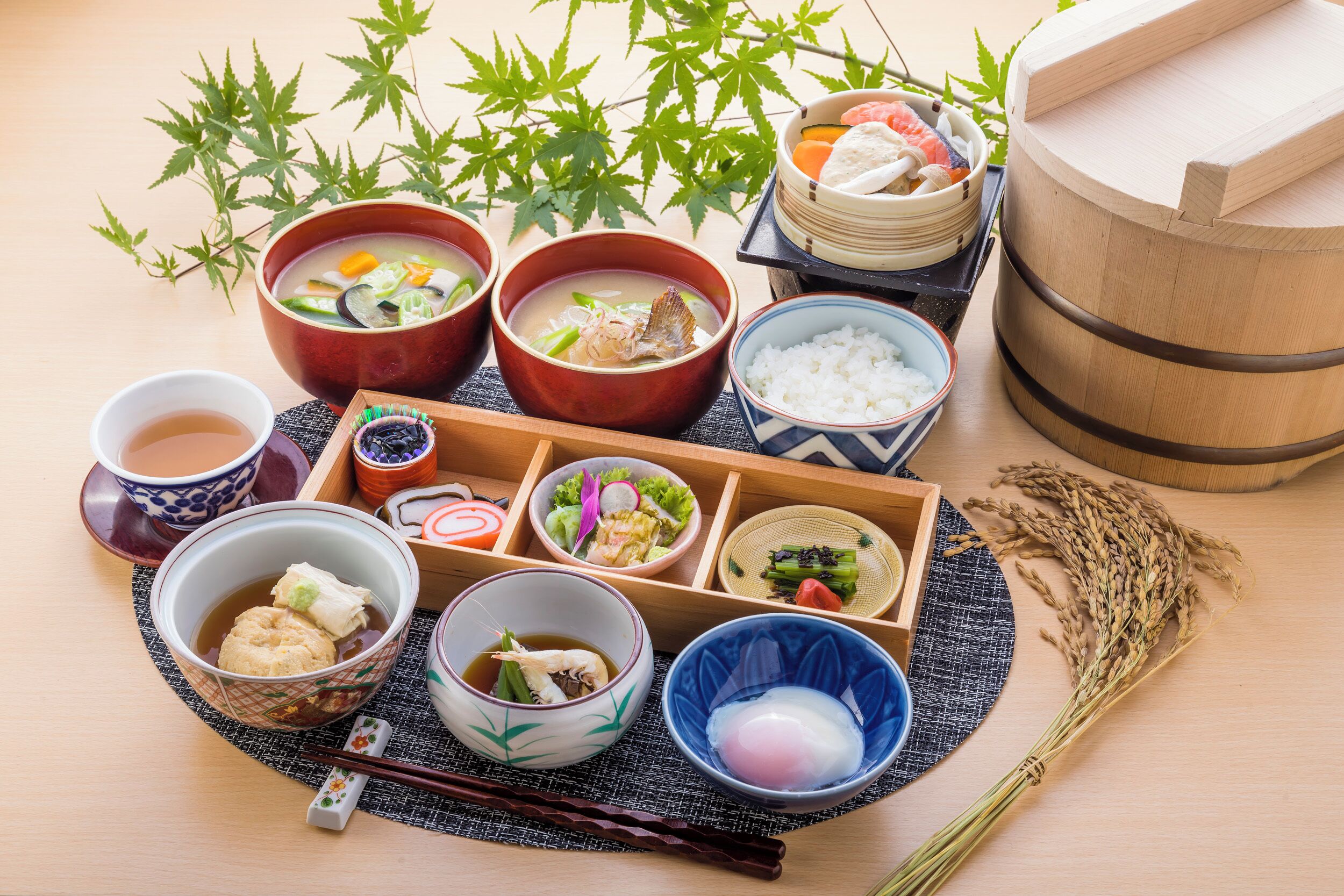 En traditionell japansk måltid bestående av olika rätter, inklusive skålar med soppa, ris och inlagda grönsaker, som är upplagda på ett träbord.