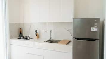 A modern kitchen with white cabinets, a stainless steel refrigerator, and a marble backsplash.