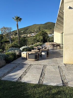 En terrasse med udendørs møbler og udsigt til en bakke.