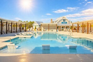 A swimming pool with lounge chairs, a covered area, and a building with a sign.