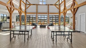 Een ruime hal met hoge plafonds en grote ramen, met tafels en stoelen klaar voor bijeenkomsten.