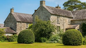 A stone building with multiple chimneys, surrounded by well-maintained hedges and a grassy lawn. - Ty Fry Estate - sleeps 16 guests  in 8 bedrooms (Pentraeth/Red Wharf Bay)