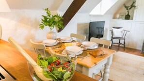 A dining area with a table set for four, a bowl of salad in the foreground, and a plant in the background. - Ty Fry Estate - sleeps 16 guests  in 8 bedrooms (Pentraeth/Red Wharf Bay)