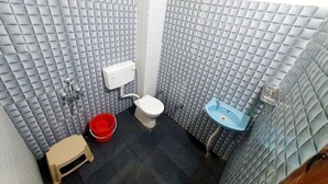 Un baño pequeño con inodoro, lavamanos y un cubo rojo.