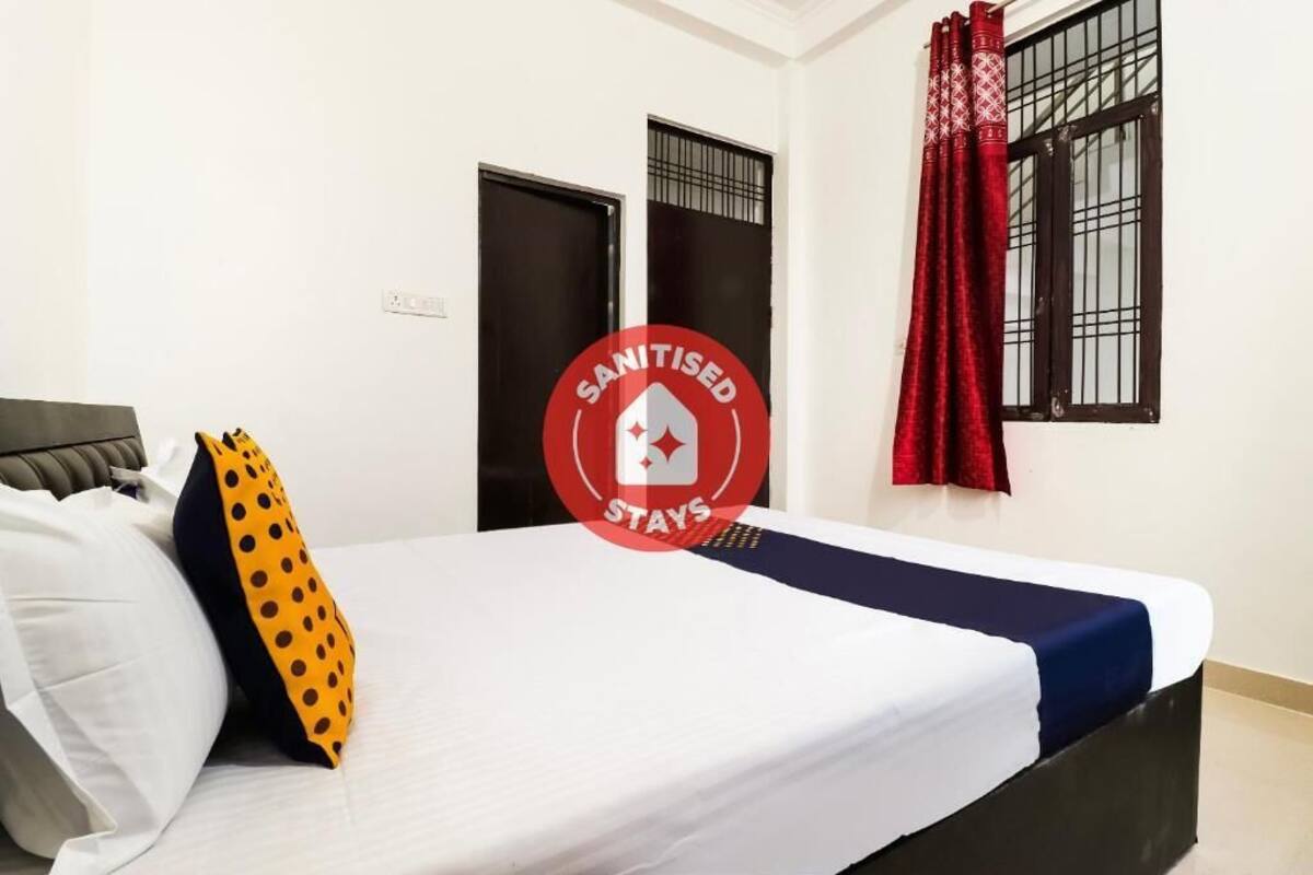 Una habitación de hotel con una cama, almohadas, una ventana con cortinas y una puerta.