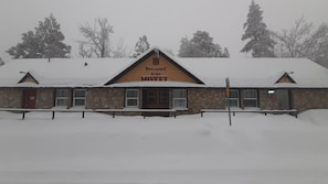 Un motel à la façade en pierre, doté de nombreuses fenêtres et d’une enseigne indiquant qu’il s’agit du Sherwood Arms Motel.