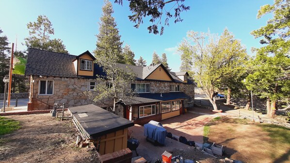 A two-story stone house with a covered patio and a small shed.