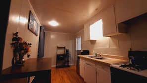 A compact kitchen with a wooden countertop, a sink, and a stove. There is a coffee maker and a vase with flowers on the counter. - SHERWOOD ARMS MOTEL_CABIN #2 (Running Springs)