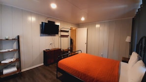 Une chambre à coucher avec un lit superposé, un téléviseur fixé au mur, une table de chevet et une armoire.