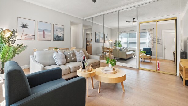 Ett modernt vardagsrum med en soffa, ett soffbord och en stor spegel som reflekterar rummet.