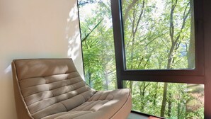 A room with a large window, a woven chair, and a red rug. - A treehouse in the heart of La Roche (La Roche en Ardenne)