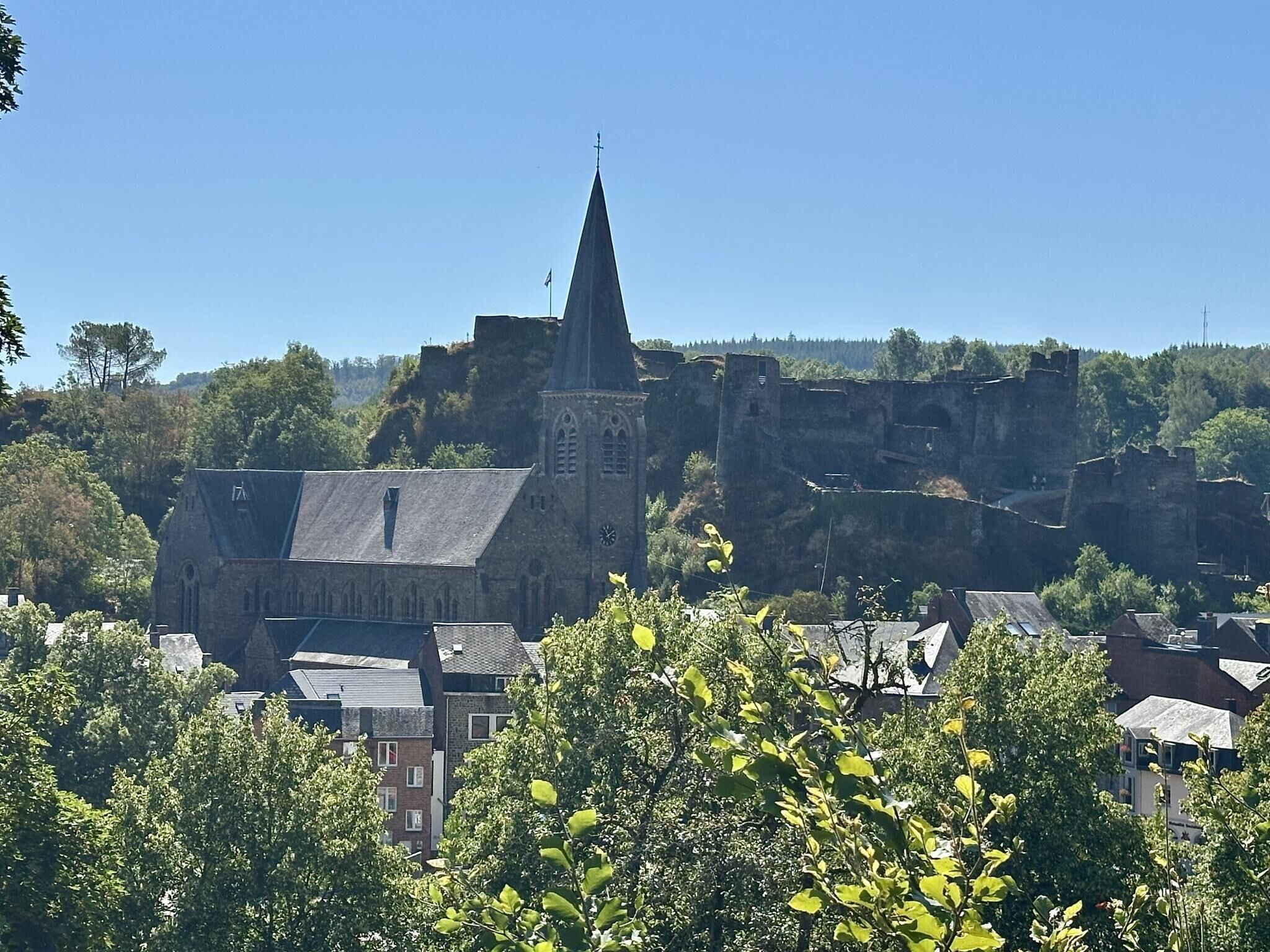 Un bâtiment historique doté d’une tour imposante et d’une horloge, entouré d’arbres et d’autres bâtiments.