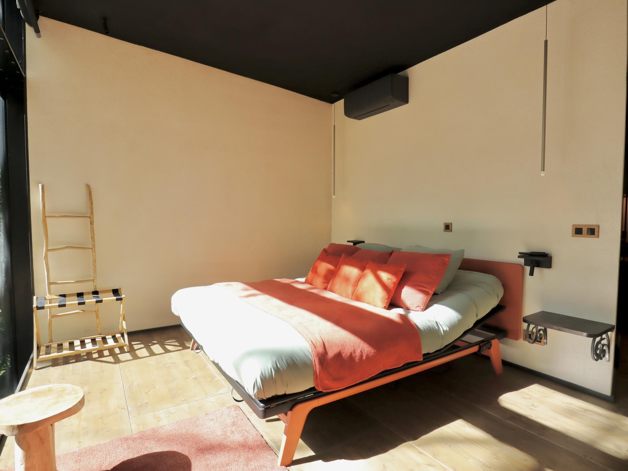 A bedroom with a bed, a wooden ladder, a small table, and a shelf.
