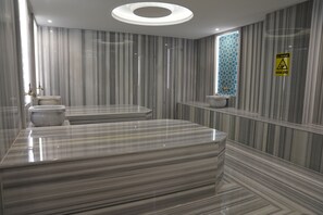 Een moderne badkamer met streepjesmarmeren wanden, een centraal geplaatst wastafel en een raam met een geometrisch patroon.
