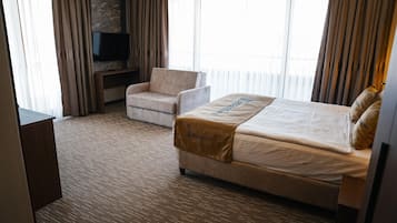 A hotel room with a bed, a chair, a TV, and a carpeted floor.