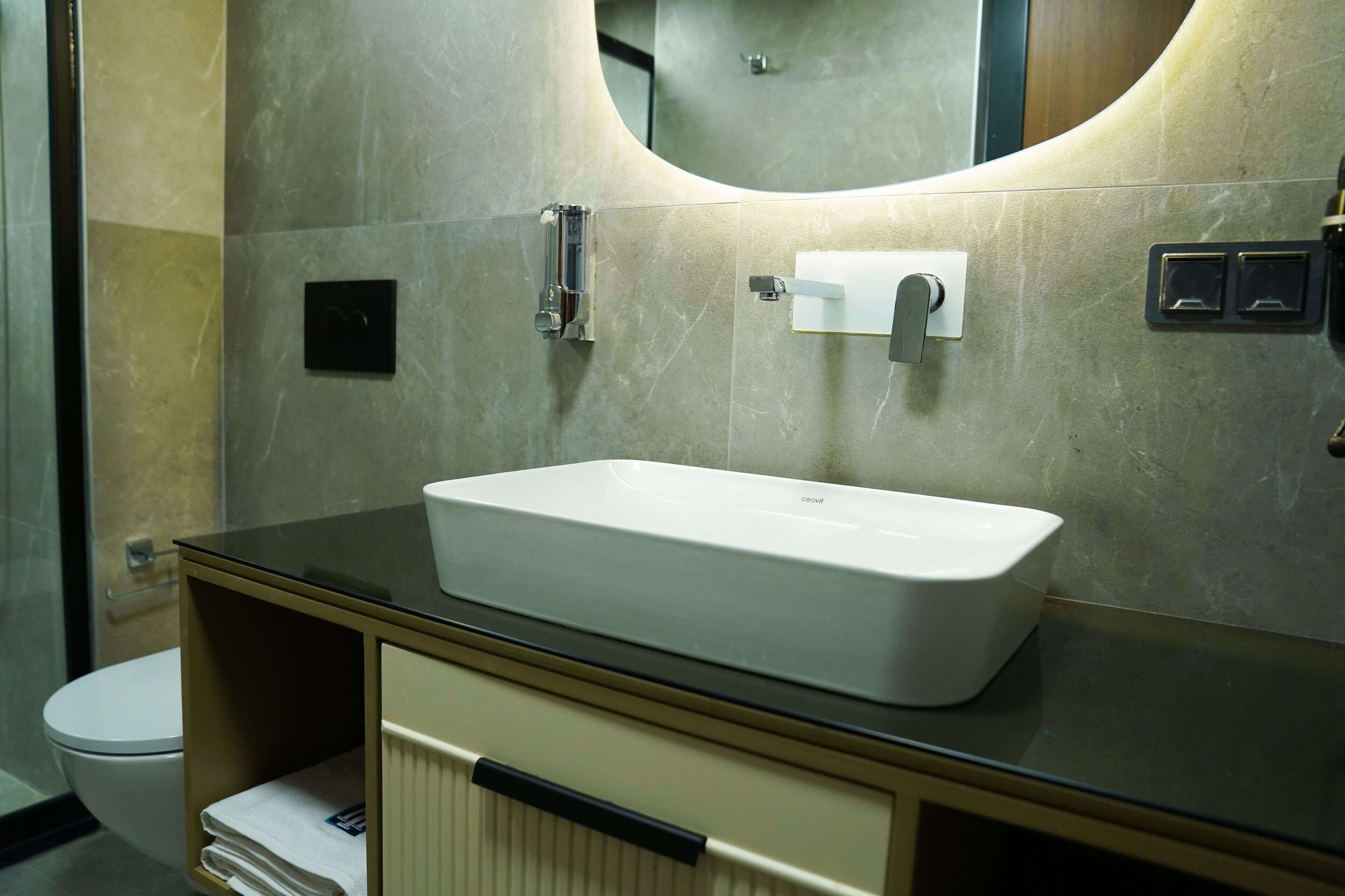 Une salle de bain moderne avec un grand lavabo, des toilettes et un miroir.