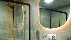 A modern bathroom with a glass-enclosed shower, a large mirror, and a vanity with a sink. - Tetrainn Hotel (Ankara)