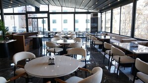 A modern dining area with round tables and cushioned chairs, large windows, and a high ceiling. - Tetrainn Hotel (Ankara)
