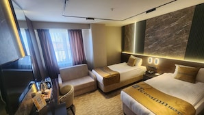 A hotel room with a bed, a sofa, a desk with a TV, and a large window with curtains. - Tetrainn Hotel (Ankara)