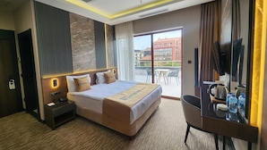 A hotel room with a bed, bedside table, desk, chair, and a view of the city through the window. - Tetrainn Hotel (Ankara)