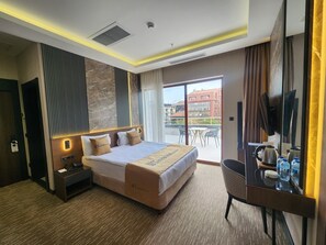 A hotel room with a bed, bedside table, desk, chair, and a view of the city through the window. - Tetrainn Hotel (Ankara)