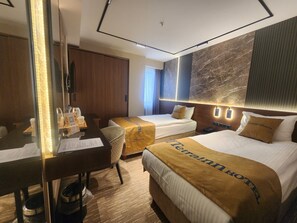 Een hotelkamer met een bureau, twee bedden, een grote spiegel en een marmeren wand.
