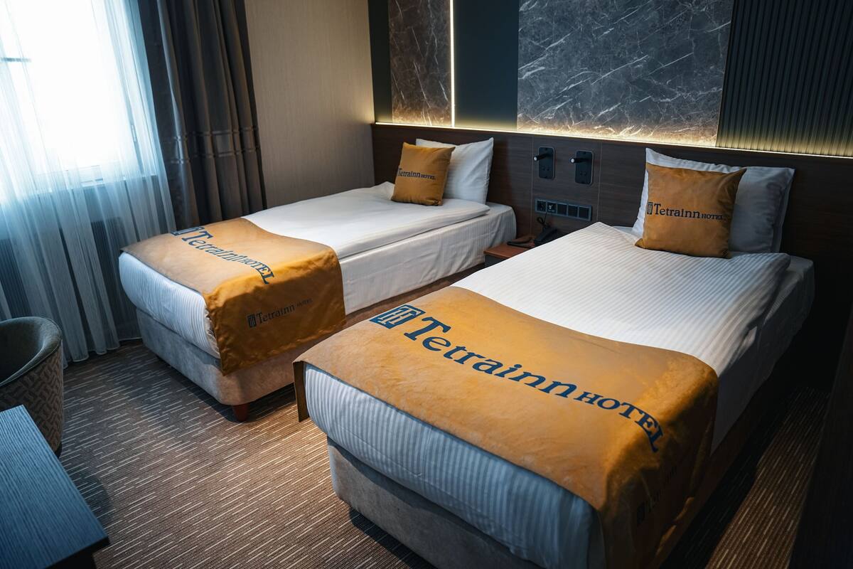 Two twin beds with matching headboards, a wooden nightstand, and a chair.