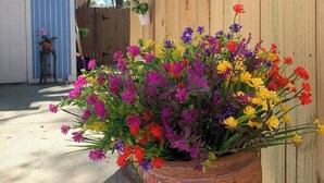 Ein Blumentopf mit bunten Blüten vor einem Holzzaun.