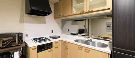 A compact kitchen with a gas stove, a microwave, and a stainless steel sink.