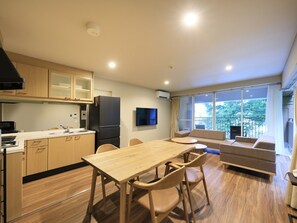 A compact living space with a kitchenette, dining area, and a balcony with a view.
