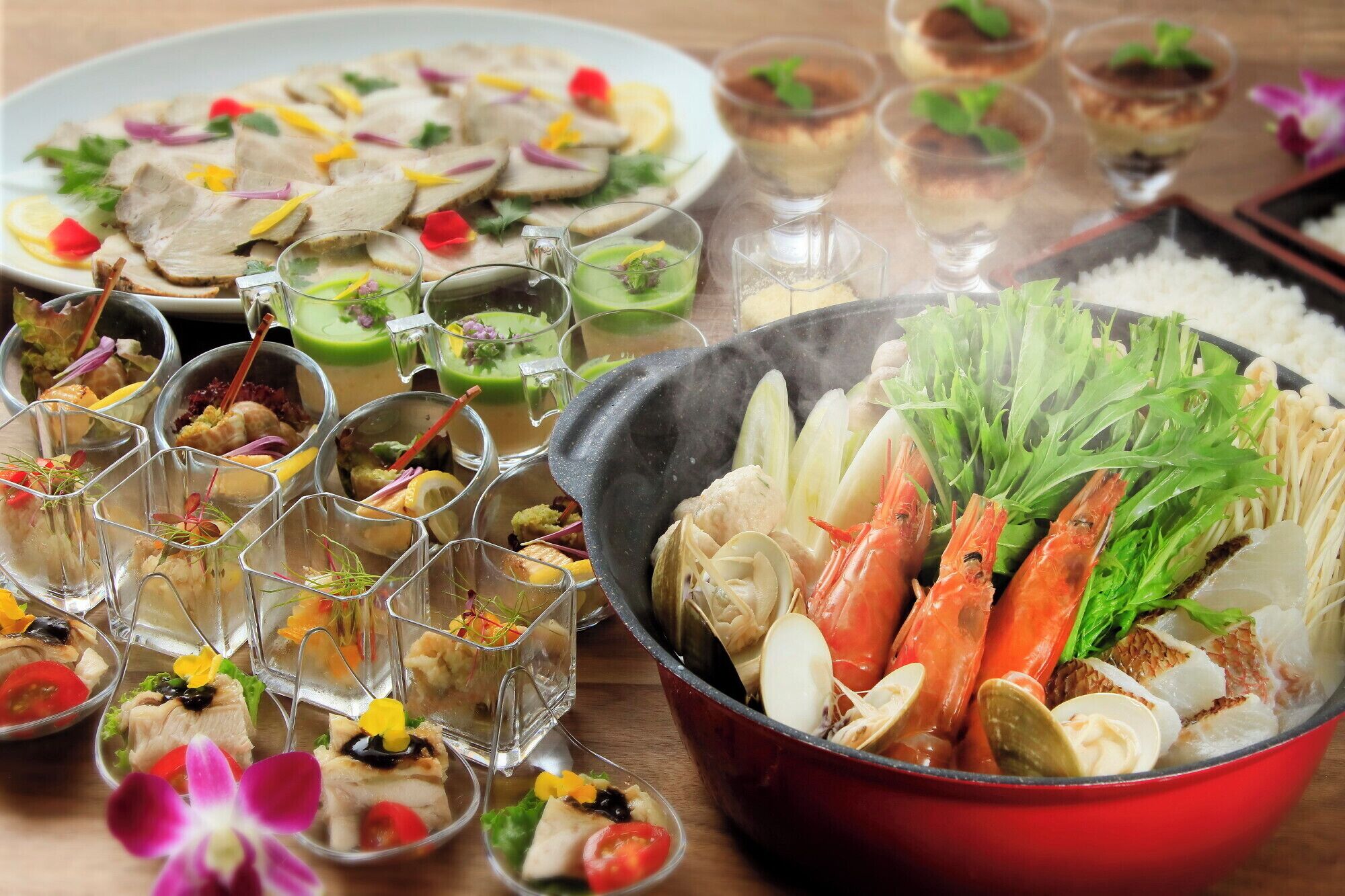 A variety of dishes including seafood, vegetables, and a hot pot with a red pot.