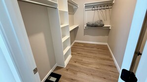 Een inloopkast met open planken, een kledingroede en een klein plankje met een tas.