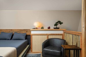 Una habitación con una cama, una silla, una mesita, un estante con adornos y una lámpara.