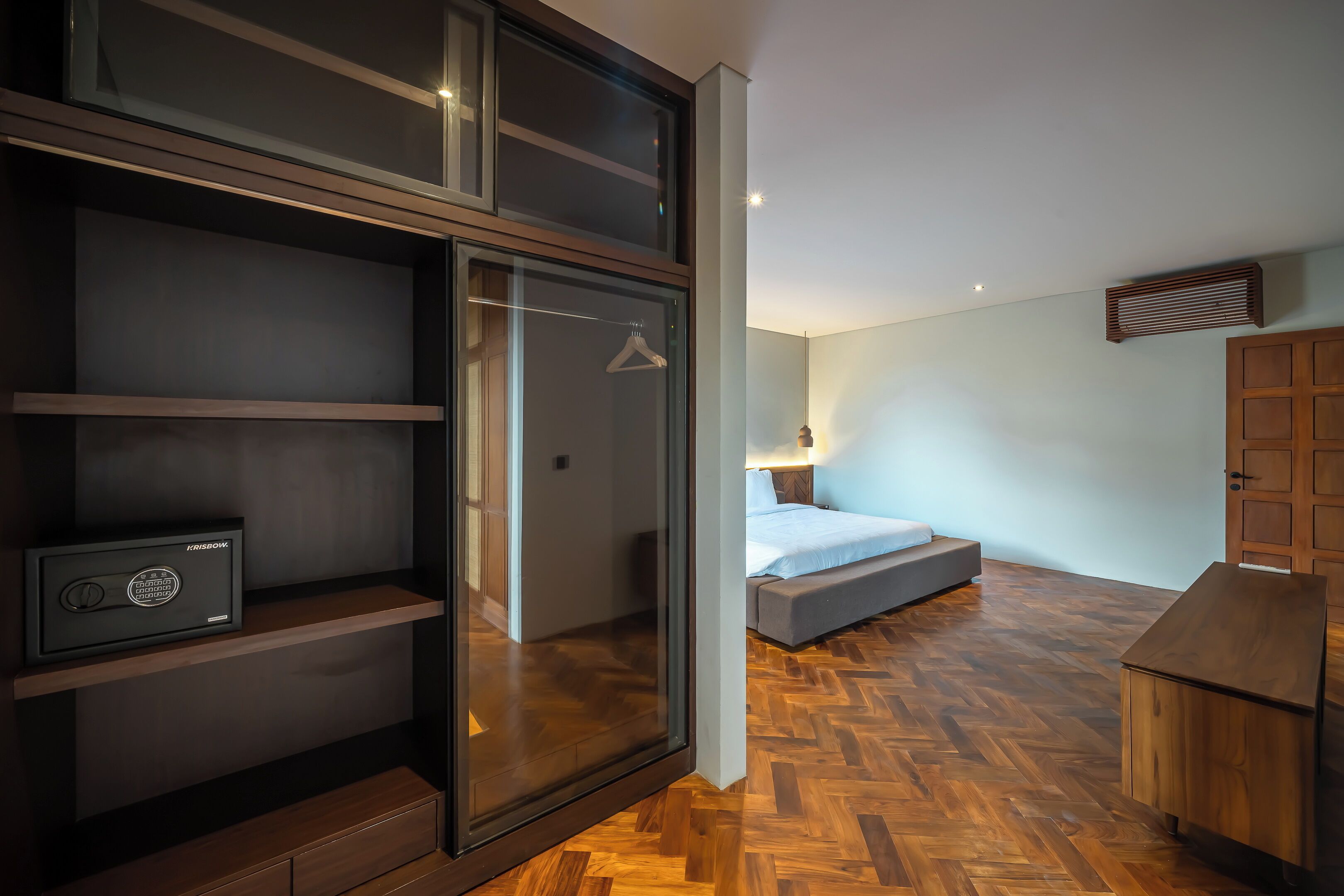 A modern bedroom with a bed, a wardrobe, and a desk with a computer.