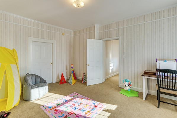 Een kinderspeelkamer met een speeltent, een zitzak, een lettermat en een klein tafeltje met stoel.