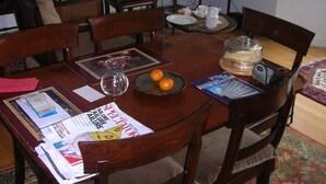 A dining area with a wooden table, chairs, and a television in the background.