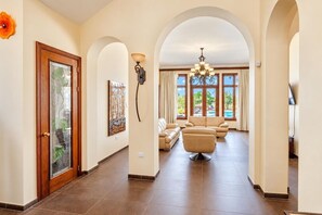 A spacious hallway with a wooden door, a wall-mounted artwork, and a seating area with a sofa and armchairs.