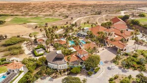 Un resort con piscina, campo de golf y vistas a la playa.
