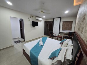 Habitación de hotel con cama, televisión, aire acondicionado, una silla y un escritorio.