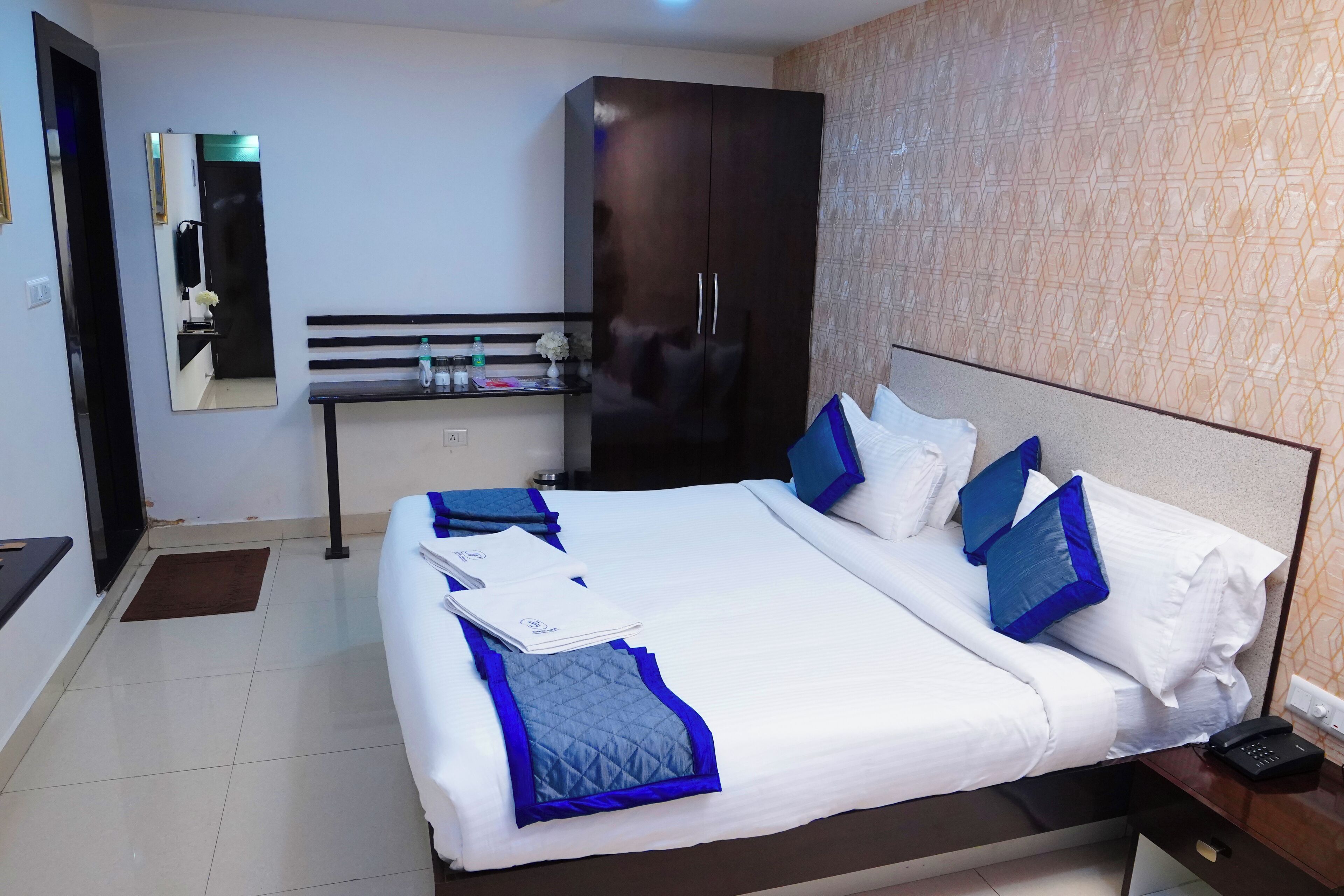 Una camera d'albergo con un letto grande, un armadio, una panca e uno specchio.