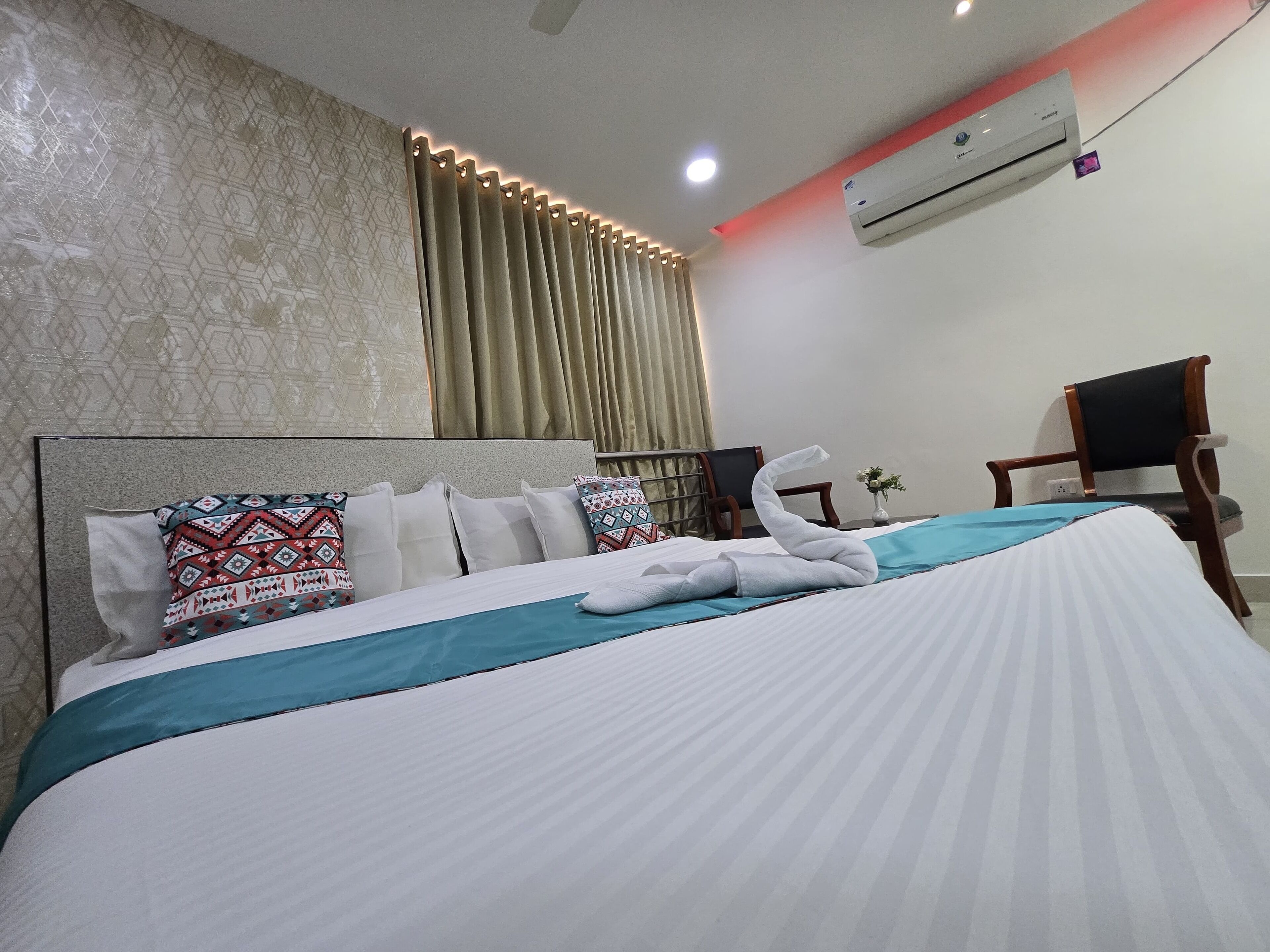Une chambre d’hôtel avec un lit bien fait, une chaise, un appareil de climatisation et un rideau.