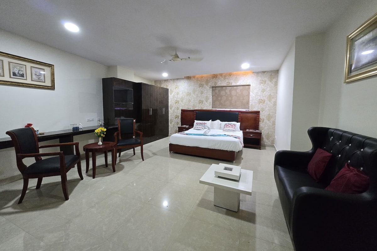 A modern hotel room with a bed, a sofa, a desk, and a chair.
